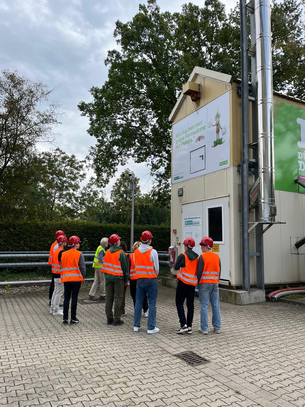 Man sieht die Schüler:innengruppe auf dem Gelände des  Biomasseheizkraftwerks in Düsseldorf Garath.